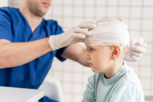 boy getting his head bandaged by a doctor