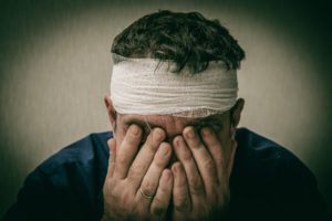 man with a head bandage with his head in his hands