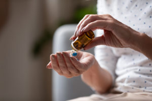 woman pouring pills from a medication bottle into her hand