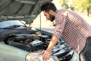 young man looking under the hood of a car