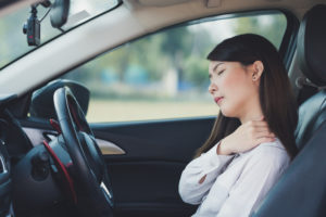 a woman driving a car has shoulder and neck pain