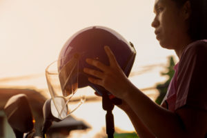 a woman prepares to put on a motorcycle helmet